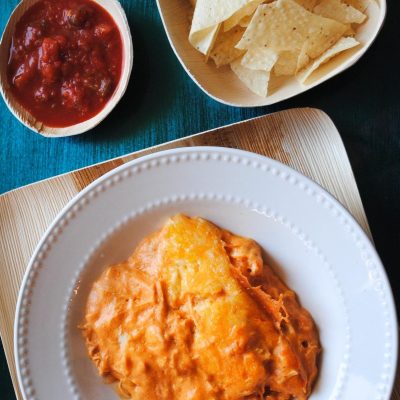 serving of CrockPot chicken enchilada casserole in white bowl served with tortilla chips and salsa