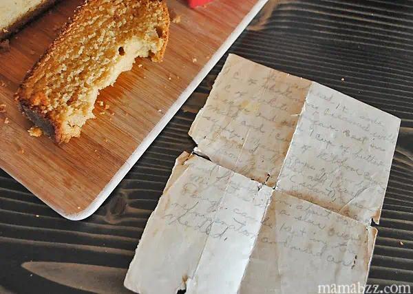 slice of gingerbread loaf on wood cutting board beside Grandma's torn and tattered recipe