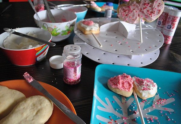 sprinkles and frosting for decorating heart cookie pops on blue and orange plates
