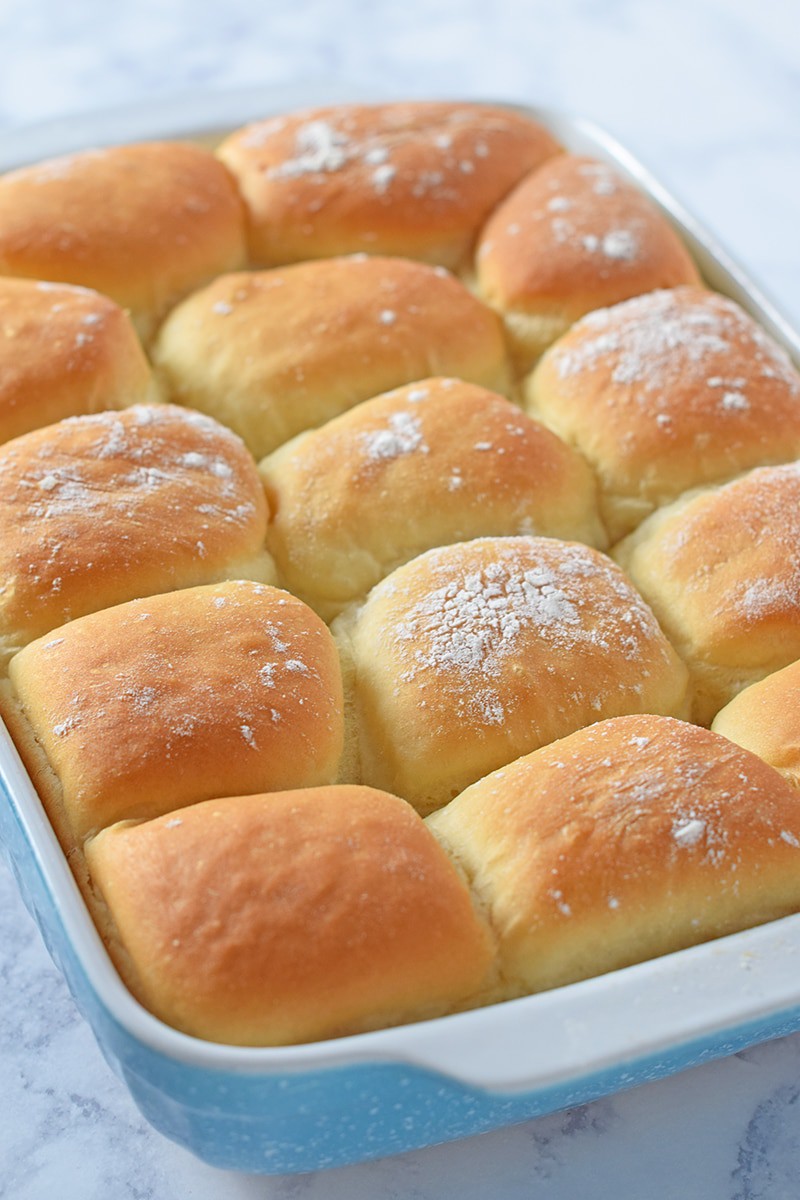 homemade dinner rolls, puffy and pillowy bread rolls, in a blue baking dish