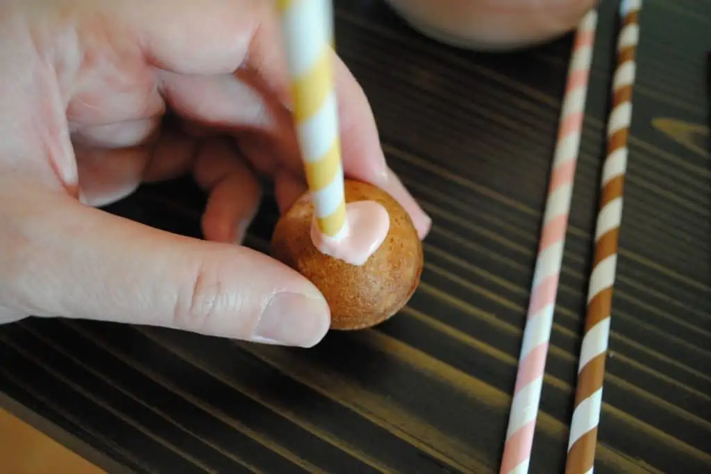 inserting paper straw into cake ball for cake pop stick