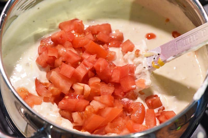 making a creamy chicken enchilada sauce with fresh tomatoes and sour cream in sauce pan
