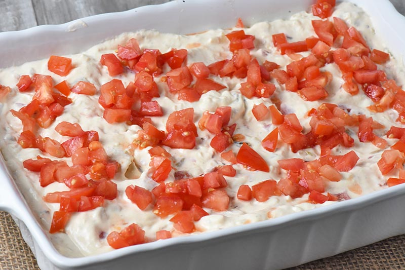 add tomatoes to top of chicken enchiladas in white baking dish