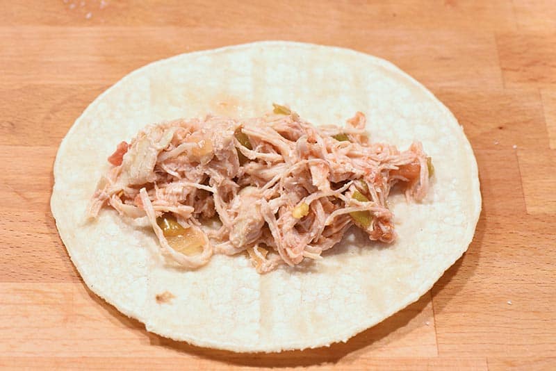 add taco chicken to corn tortilla to make chicken enchilada recipe