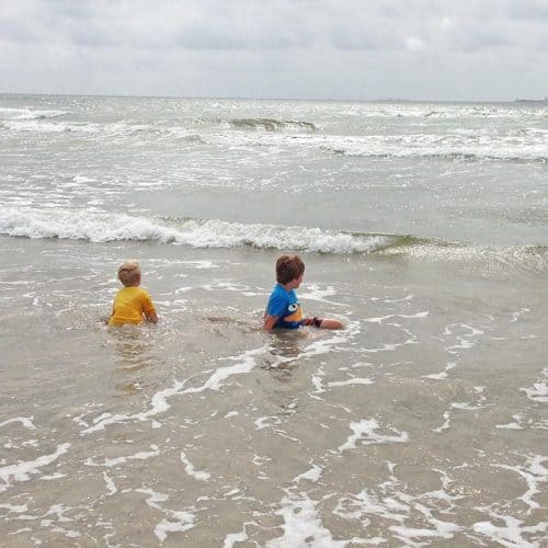 two boys playing in the waves and watching ships on San Jose Island beach