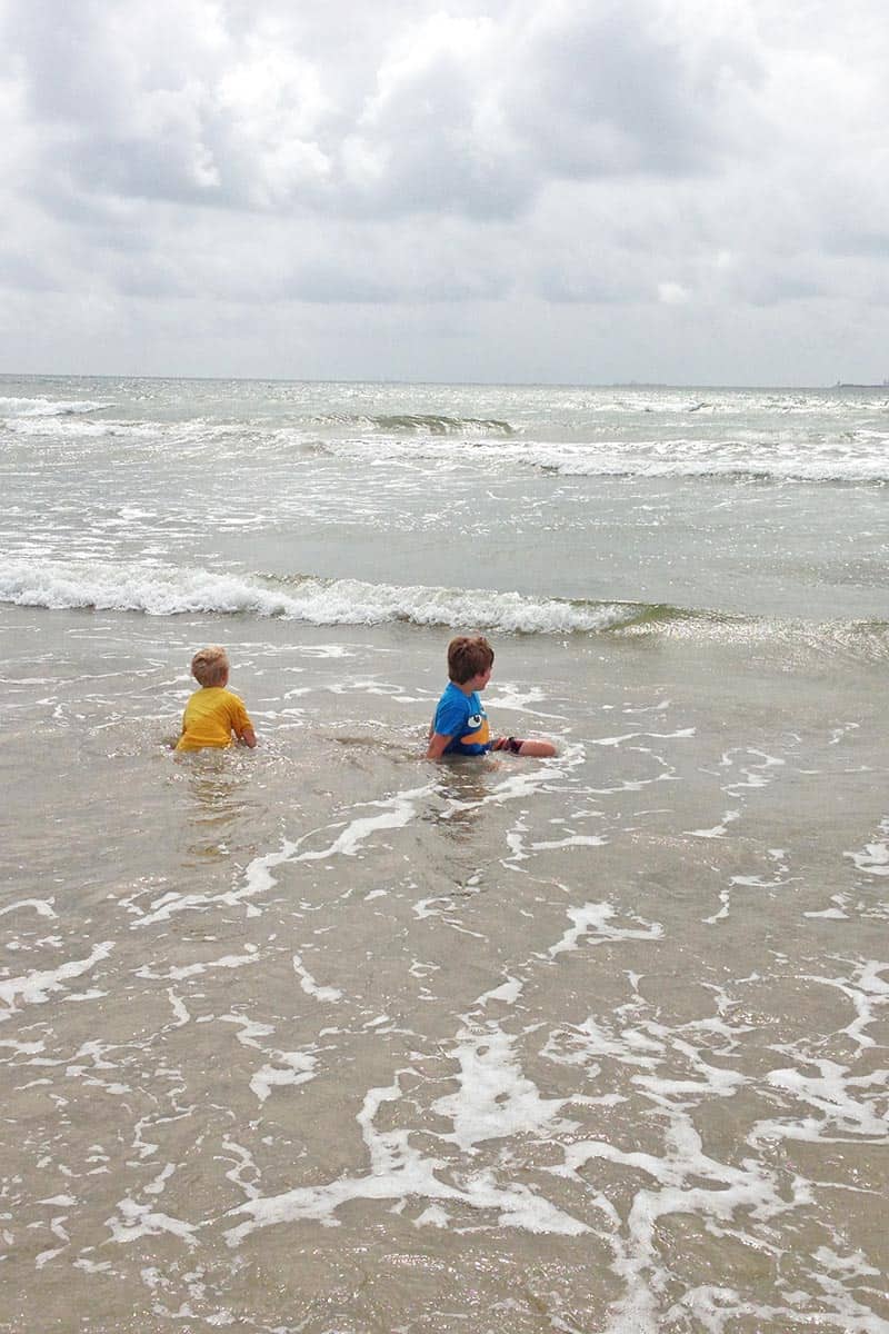 two boys playing in the waves and watching ships on San Jose Island beach in Port Aransas, Texas