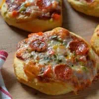 Grands Mini Supreme Pizzas are a quick and easy dinner recipe made with Grands Biscuits, topped with peppers, tomato, pepperoni, basil, and delicious pizza cheese that melts to perfection.