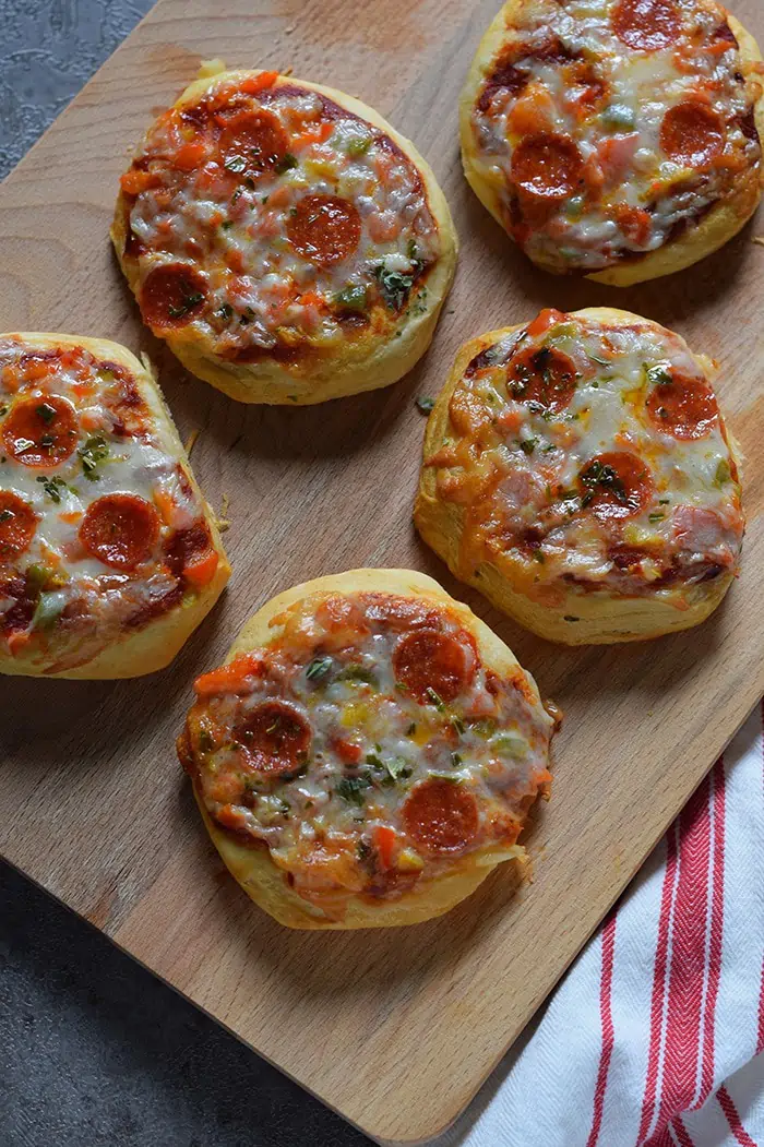 Grands Mini Supreme Pizzas are a quick and easy dinner recipe made with Grands Biscuits, topped with peppers, tomato, pepperoni, basil, and dreamy mozzarella.