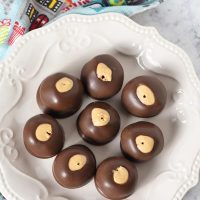 4 ingredient buckeyes peanut butter balls on ivory plate with blue Christmas kitchen towel