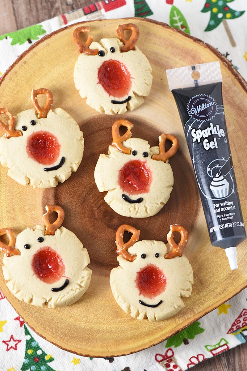 decorating reindeer thumbprint cookies with Wilton Sparkle Gel, adding eyes and mouth