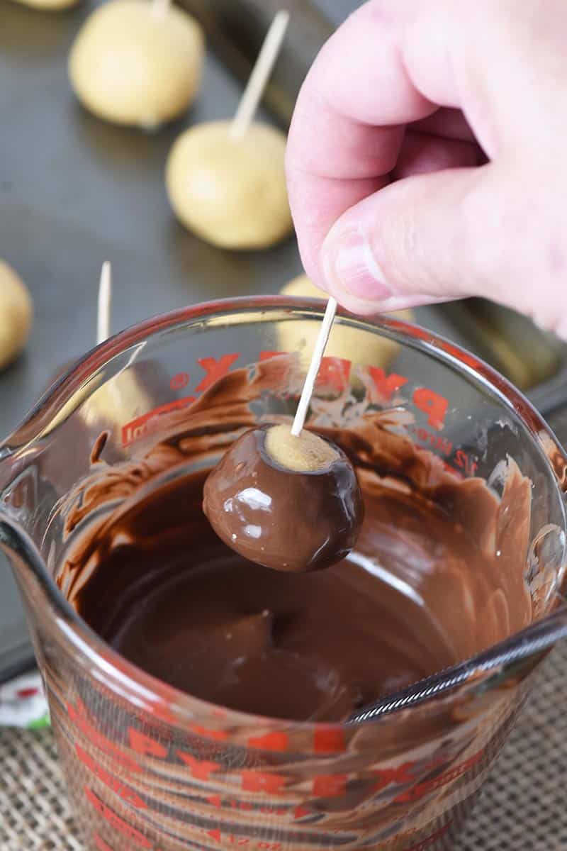 dipping peanut butter balls in chocolate in Pyrex measuring cup to make buckeye candy