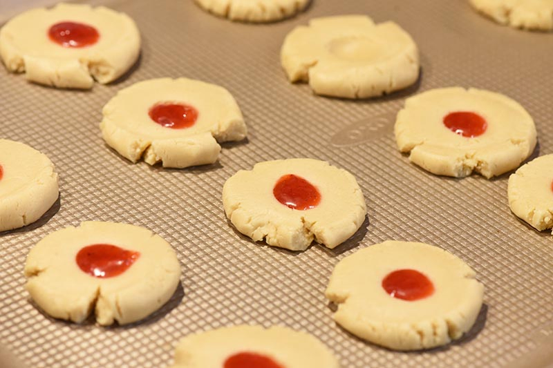 strawberry jam thumbprint cookies unbaked on cookie sheet