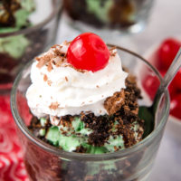 grasshopper sundae with mint chocolate chip ice cream, crushed Oreos, shaved chocolate, whipped cream, chocolate syrup, and maraschino cherry in sundae bowl with spoon