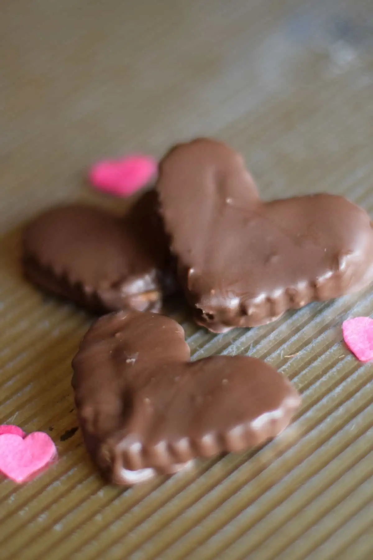 chocolate peanut butter hearts on baking sheet with pink hearts