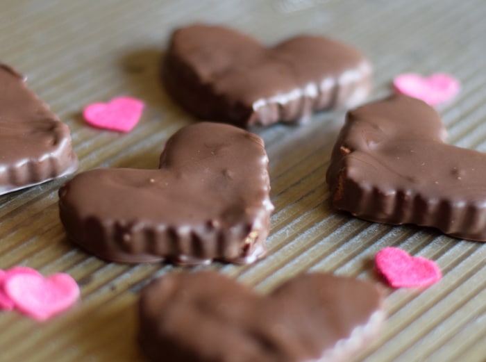 chocolate peanut butter hearts candy on baking sheet with pink hearts