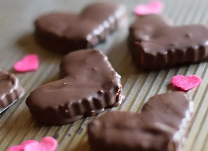 chocolate covered heart shaped peanut butter cups on baking sheet with pink hearts