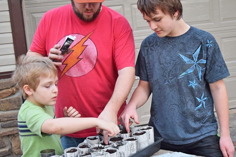 family starting seeds in newspaper seedling pots