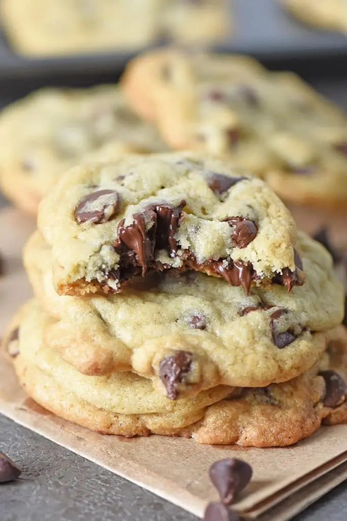 soft chocolate chip cookies stacked with melted chocolate chips and bite taken out of cookie