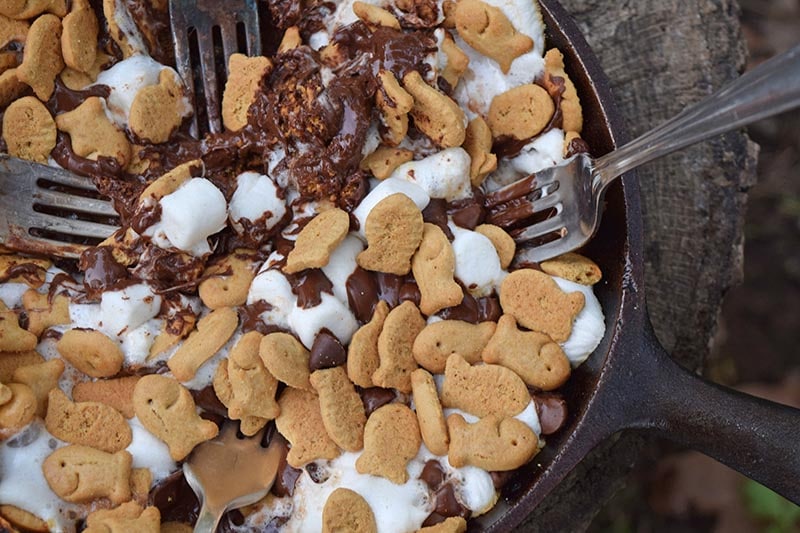 s'mores dip in a cast iron skillet with forks on a stump