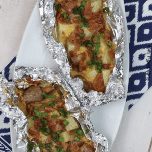 bacon campfire potatoes in aluminum foil packets on white platter