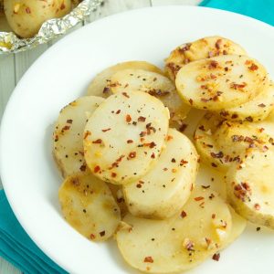 sliced campfire potatoes with seasoning on white plate