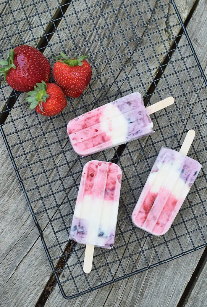 red white and blue ice pops on wire rack with fresh strawberries