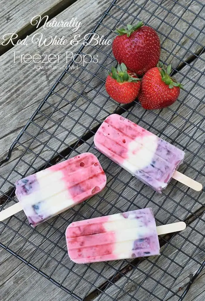 red white and blue popsicles on wire rack with fresh strawberries