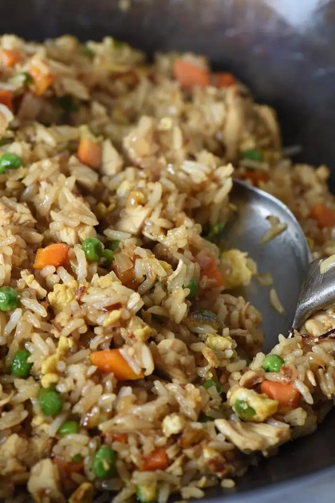 stir frying chicken fried rice with a metal spatula in a large wok