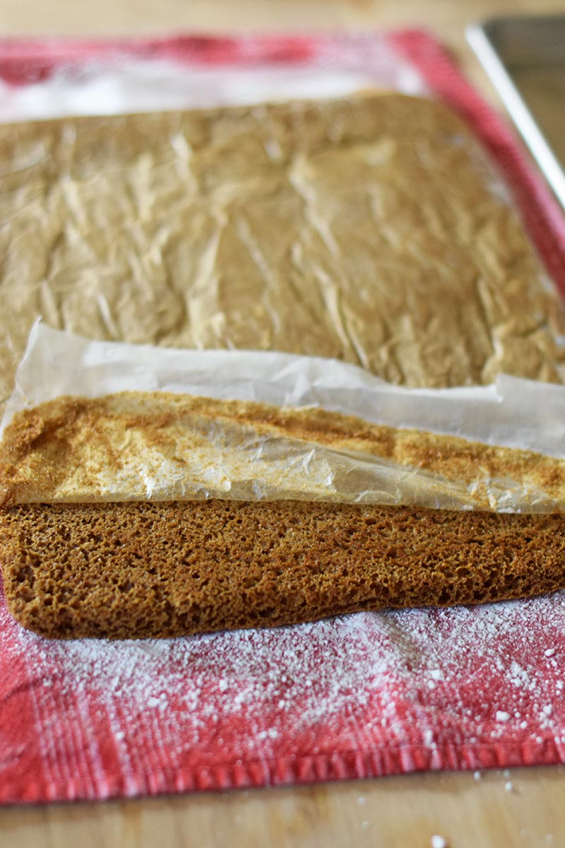place the pumpkin roll cake onto a powdered sugar flour sack towel and peel off the wax paper