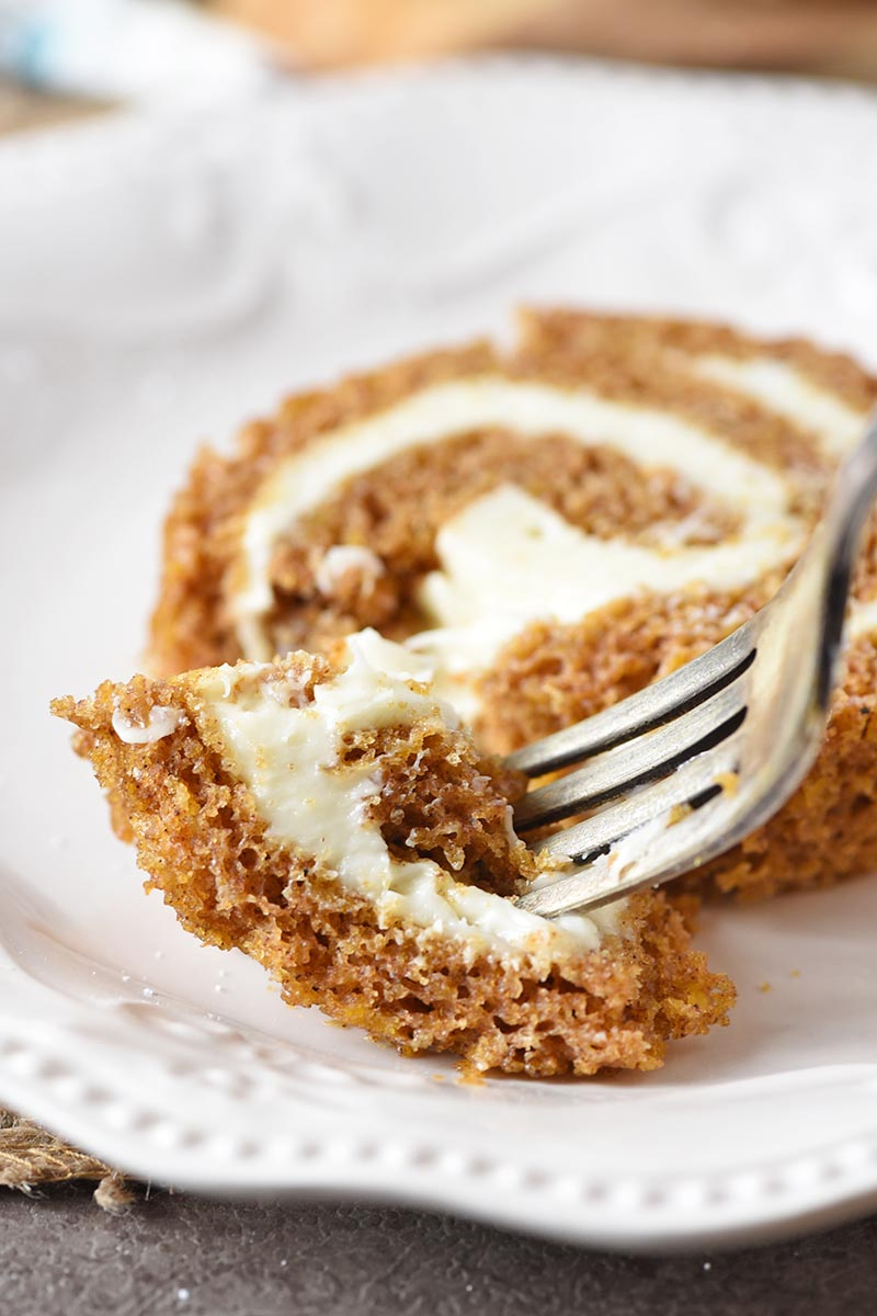 bite of pumpkin roll on a fork with ivory plate