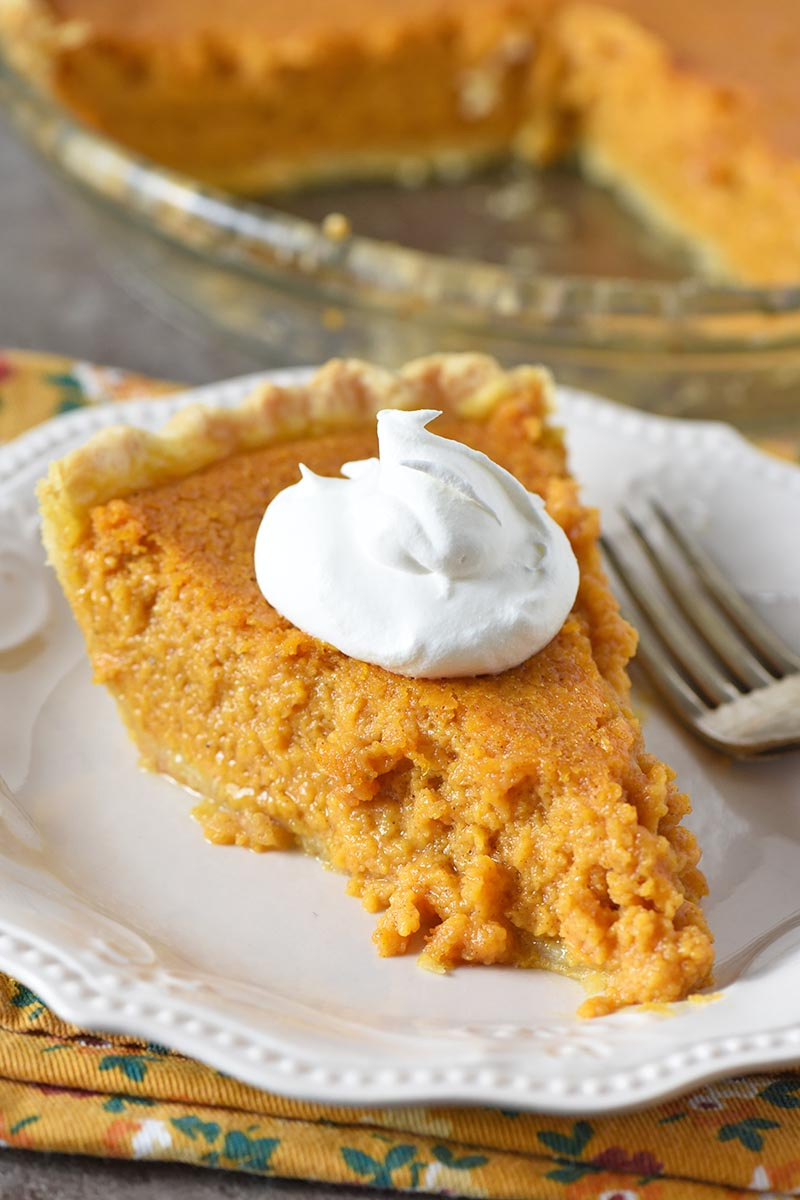 slice of sweet potato custard pie with whipped cream on white plate with fork