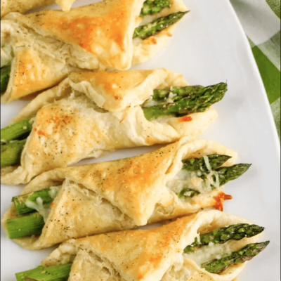 cheesy puff pastry wrapped asparagus on white platter