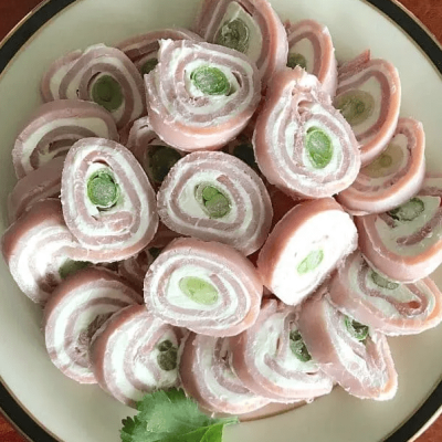 Sliced ham roll ups on white plate on wooden countertop