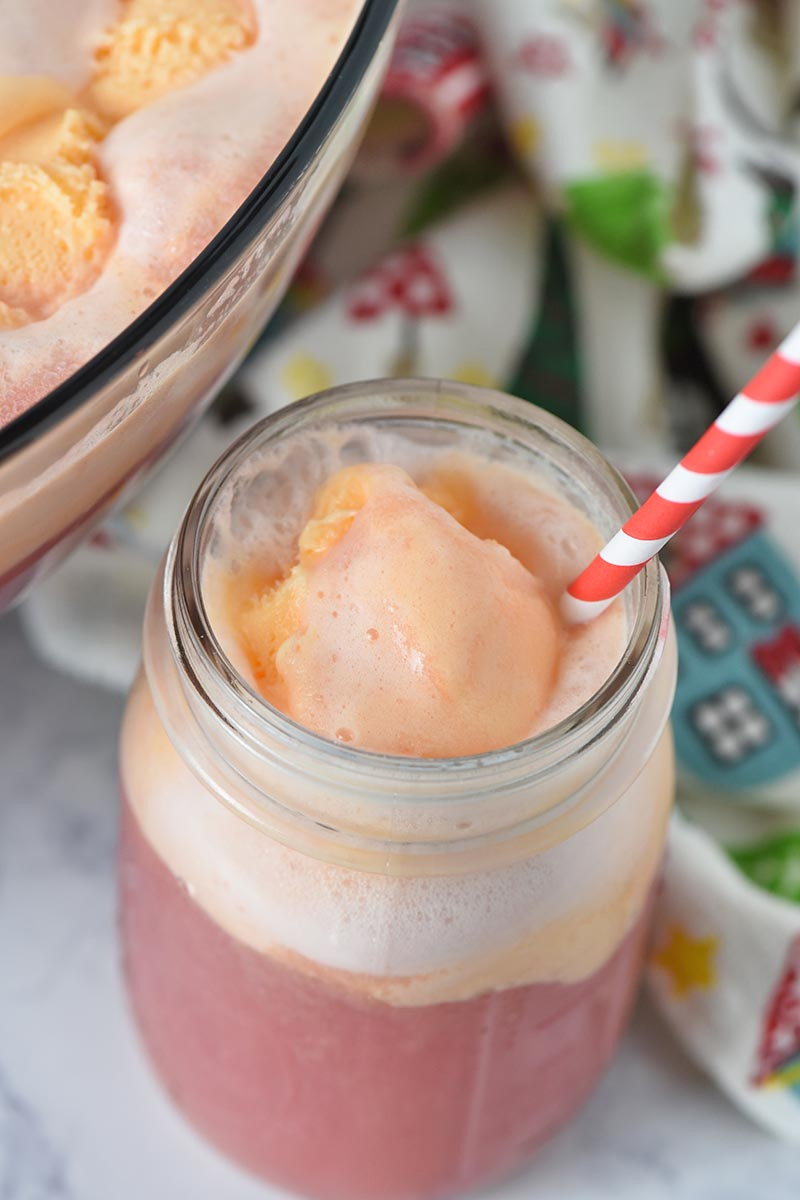 mason jar with orange sherbet punch and red and white striped paper straw