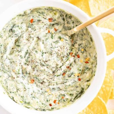 spinach dip with cream cheese in white bowl with tortilla chips