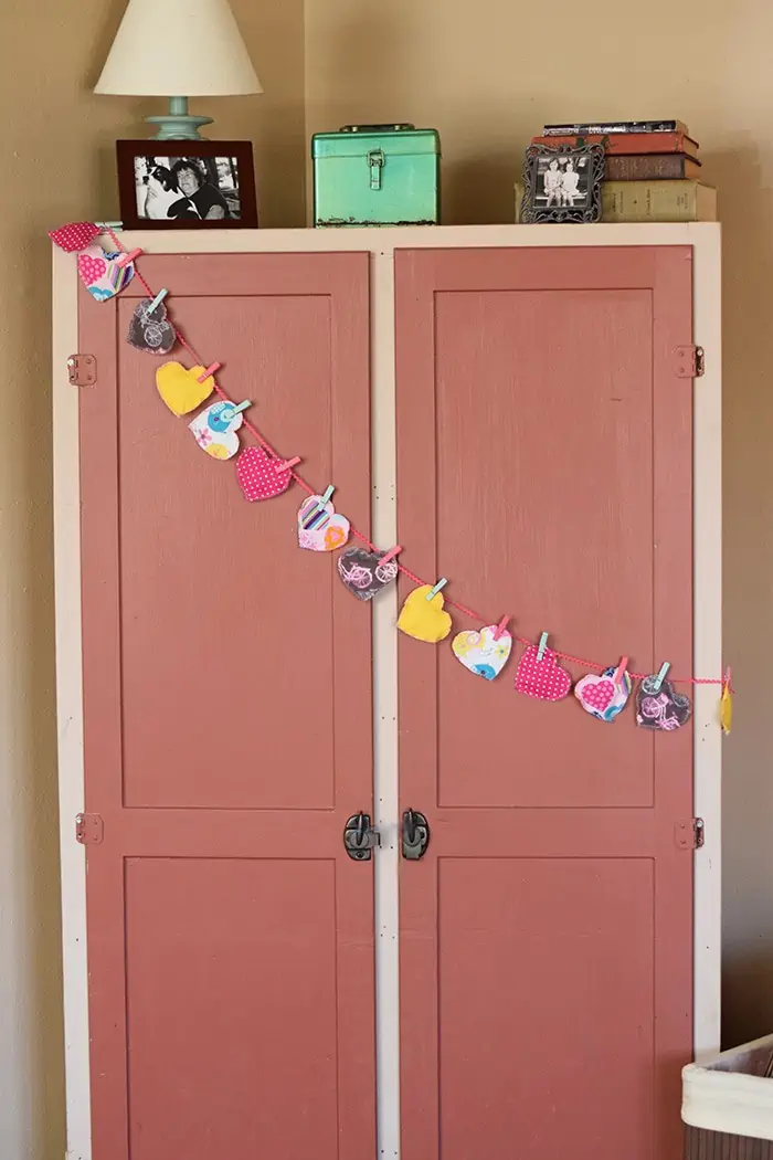 Decorate for Valentine's Day by making a super easy to sew Valentine's Day heart garland with cheap fat quarters from the fabric store. Makes the sweetest Valentine decoration and a fun craft and sewing project! 