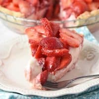 bite of strawberry cream pie on a fork with slice of pie on plate