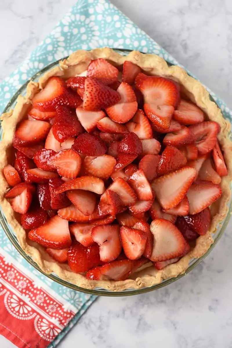 whole strawberry cream pie with fresh strawberries on a Pioneer Woman kitchen towel