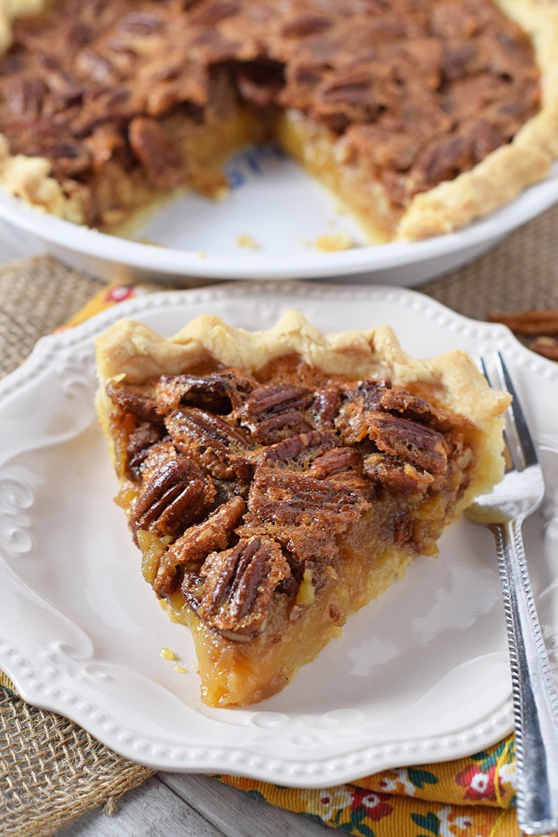 slice of classic pecan pie on white plate with fork