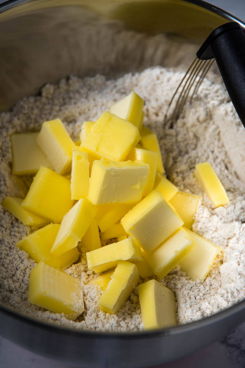 cutting butter into dry ingredients for cut out cookies with pastry blender in silver mixing bowl
