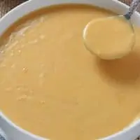 ham gravy being ladled out of a deep gray bowl with a silver spoon
