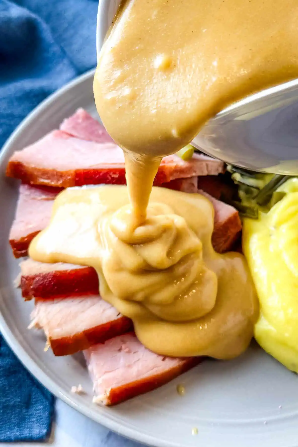 pouring homemade ham gravy from white gravy boat, pouring over home cooked ham