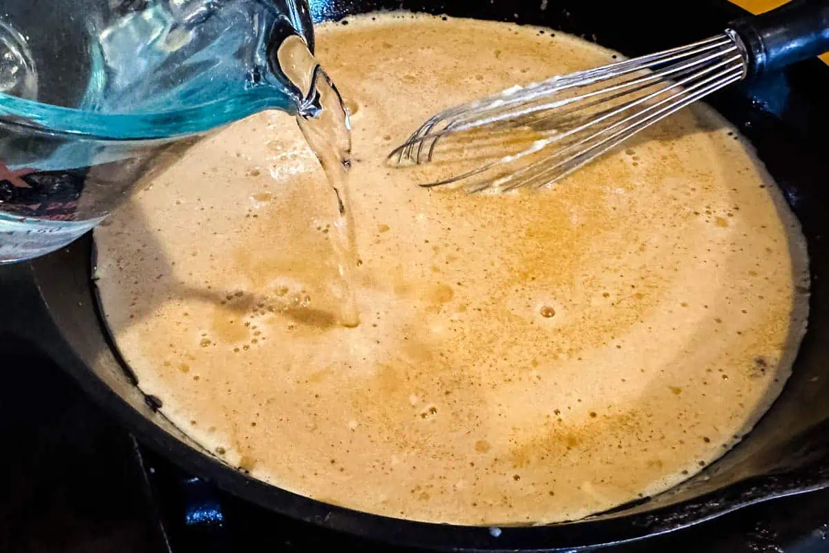 whisking water into gravy for ham in cast iron skillet