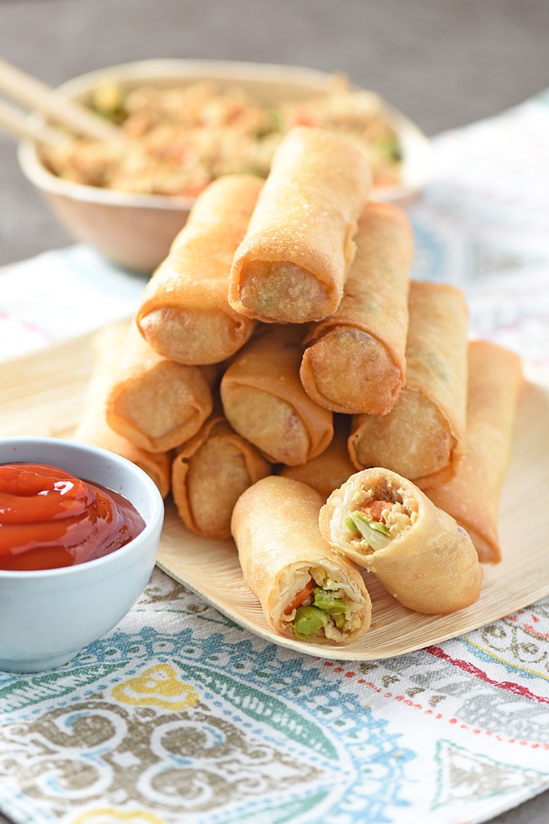 rice paper spring rolls fried to perfection and stacked on bamboo plate with one cut in half