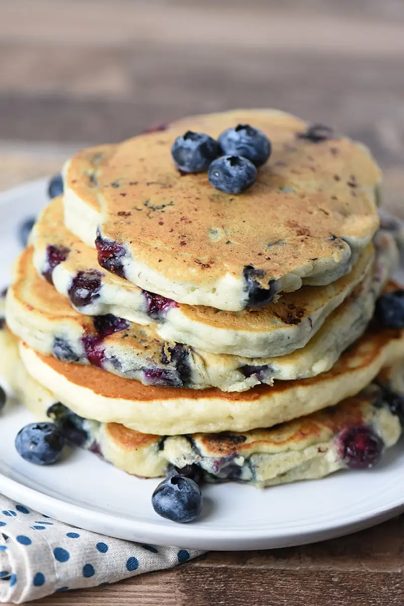 Stack of Blueberry Buttermilk Pancakes on a plate with fresh blueberries