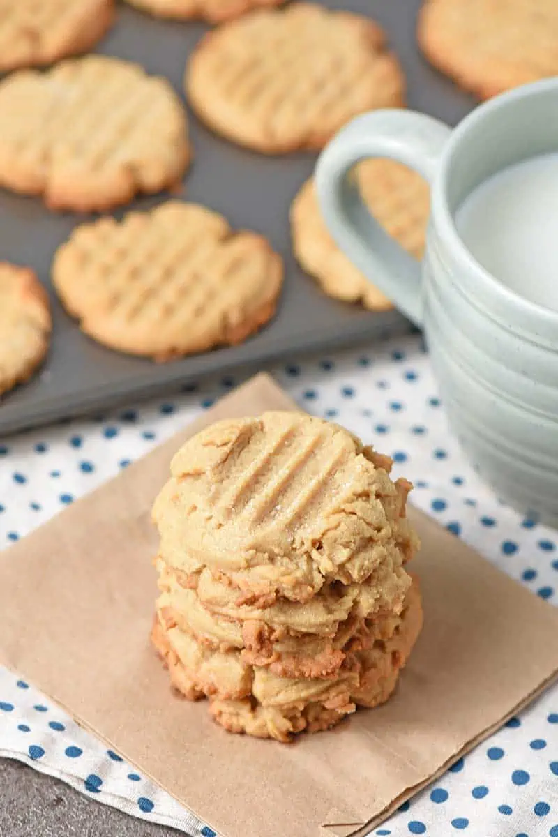 Stack of chewy peanut butter cookies on a paper bag with a cup of milk