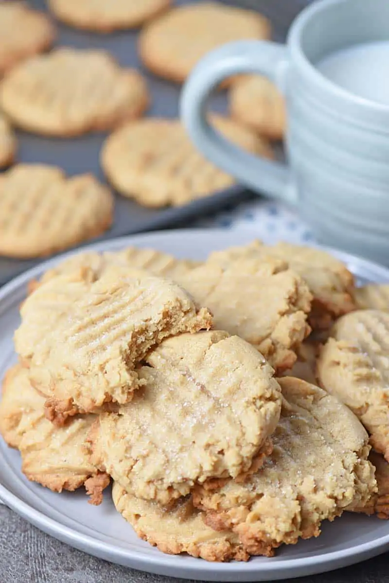 Chewy peanut butter cookies on a plate with a cup of milk
