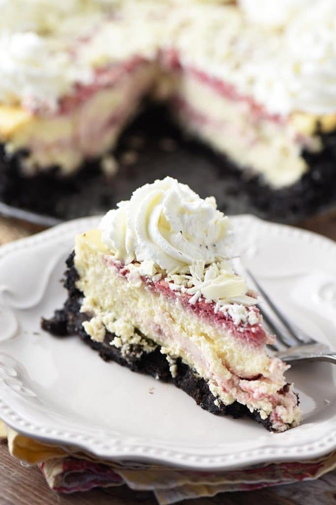slice of raspberry cheesecake with whipped cream on a white plate