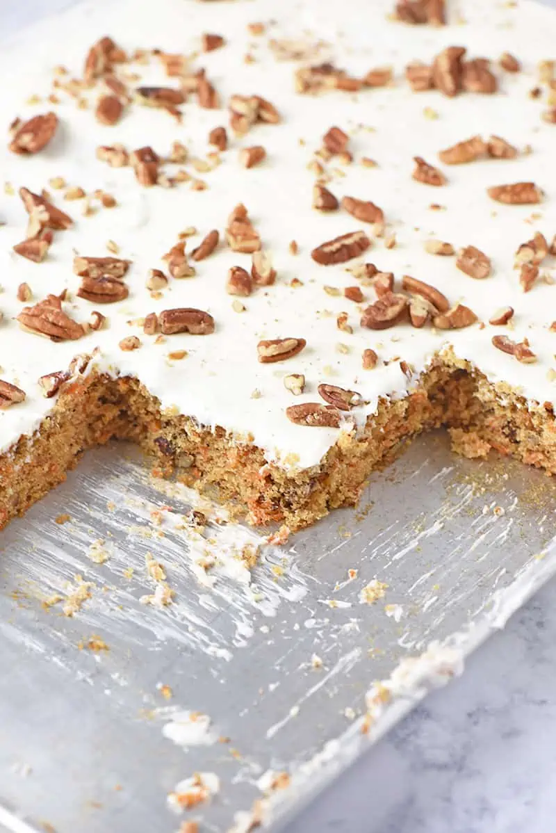 carrot cake from scratch in a sheet pan with cream cheese frosting and pecans on top