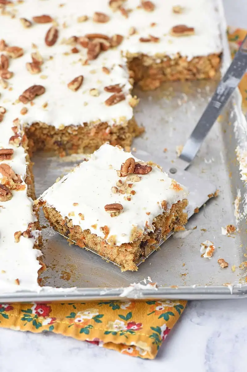 easy carrot cake recipe sliced on a spatula in a sheet pan